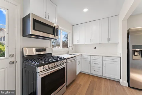 a kitchen with cabinets stainless steel appliances and wooden floor