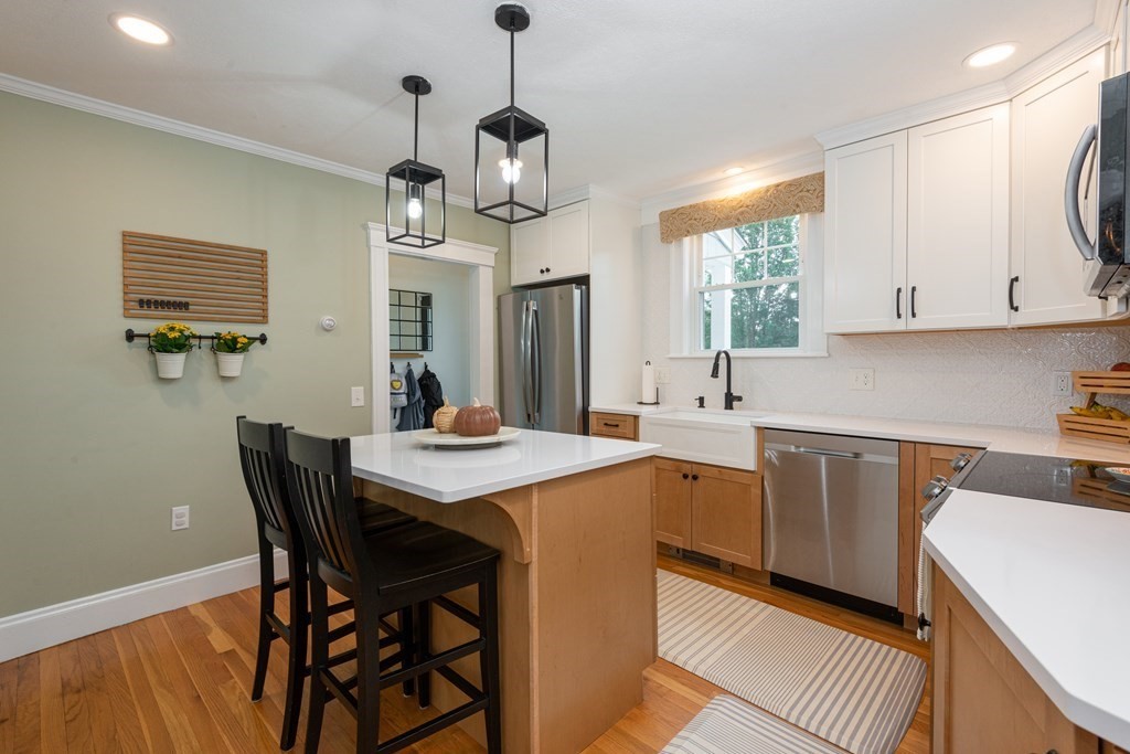 23 Trask Street Danvers, MA 01923 - Photo 8 of 42 a kitchen with stainless steel appliances a white table chairs and a wooden floor