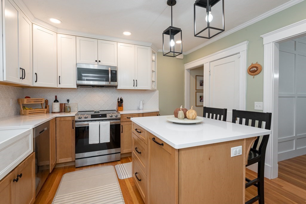 23 Trask Street Danvers, MA 01923 - Photo 9 of 42 a kitchen with stainless steel appliances kitchen island a table chairs sink and cabinets