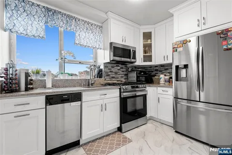 a kitchen with stainless steel appliances granite countertop a refrigerator stove a sink and a microwave