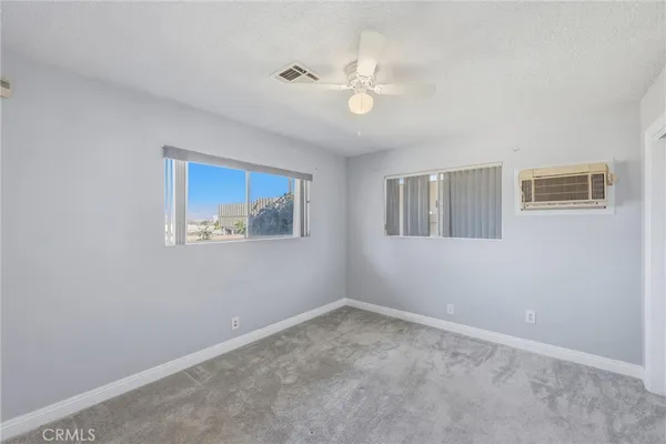 an empty room with a window and ceiling fan