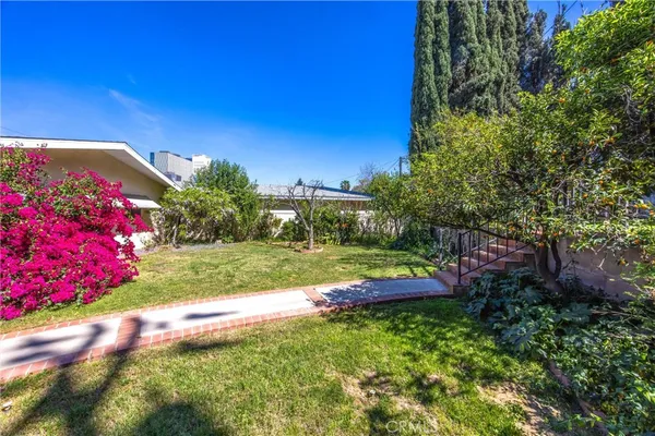 a view of a backyard with fountain and large trees