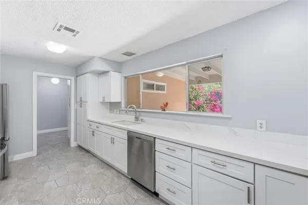 a kitchen with granite countertop a sink cabinets and stainless steel appliances