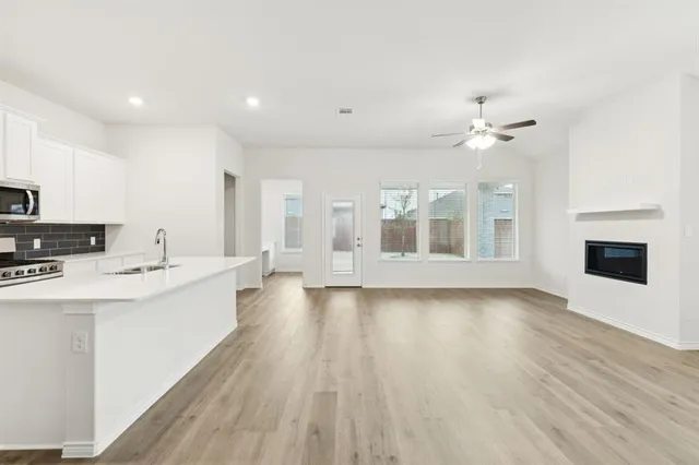 a large white kitchen with sink and dishwasher with wooden floor