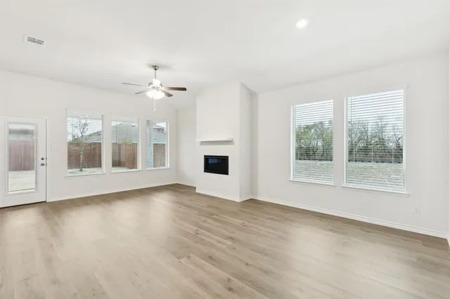 a view of an empty room with a window and wooden floor