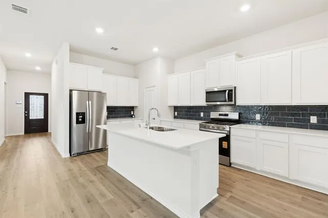 a kitchen with stainless steel appliances a refrigerator stove microwave and sink