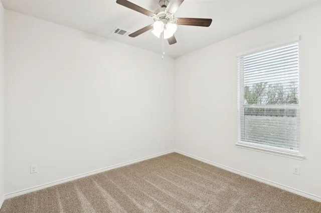 an empty room with a window and a fan