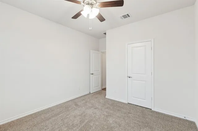 an empty room with a chandelier fan and closet