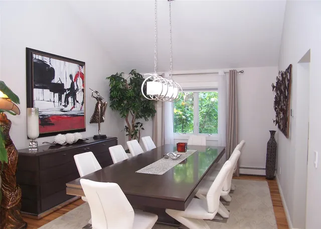 a dining room with furniture a large window and potted plants