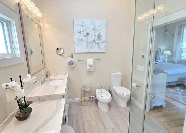 a bath room with a toilet a sink and a mirror