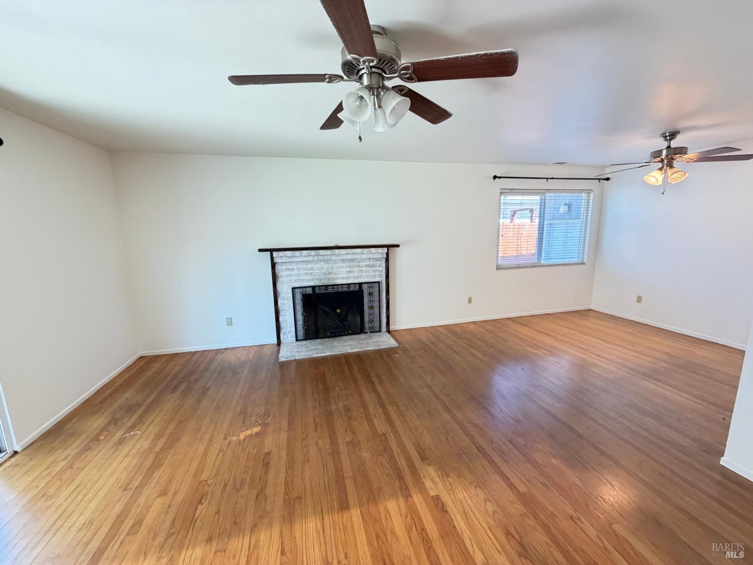 991 Rolling Green Drive Rio Vista, CA 94571 - Photo 15 of 30 an empty room with wooden floor a ceiling fan and fireplace