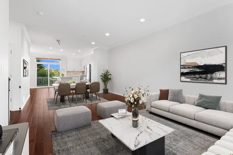 a living room with furniture kitchen view and a large window