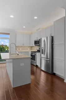 a kitchen with kitchen island a counter top space a refrigerator and a stove top oven