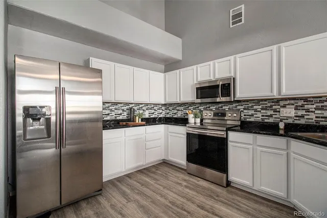 a kitchen with granite countertop a refrigerator stove and microwave