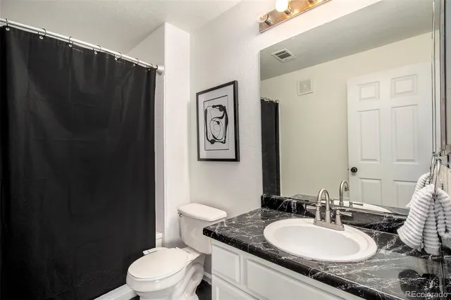a bathroom with a granite countertop sink toilet and a mirror