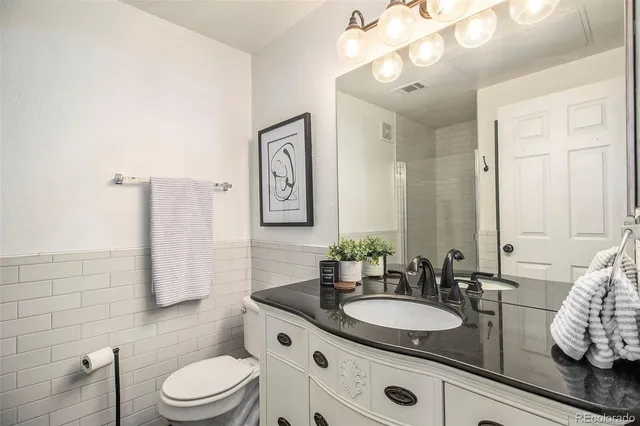 a bathroom with a granite countertop sink mirror vanity and toilet