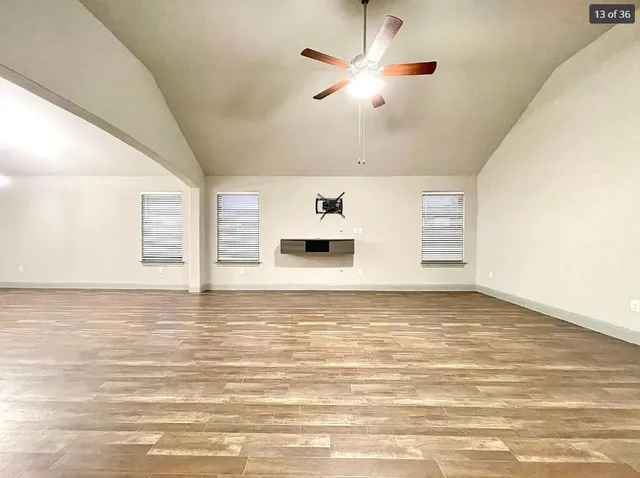 a view of empty room with wooden floor and fan
