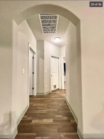 a view of a hallway with wooden floor and a chandelier
