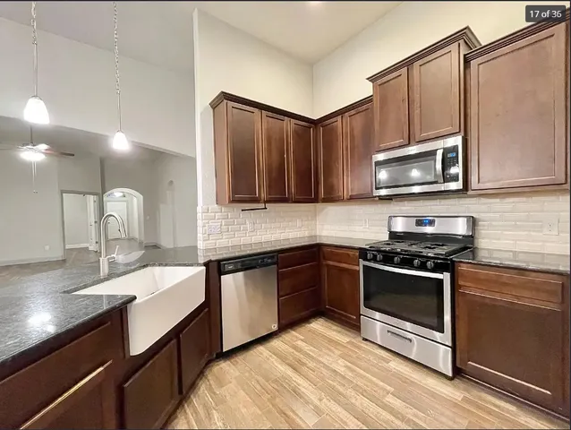 a kitchen with stainless steel appliances granite countertop a sink a stove microwave and cabinets