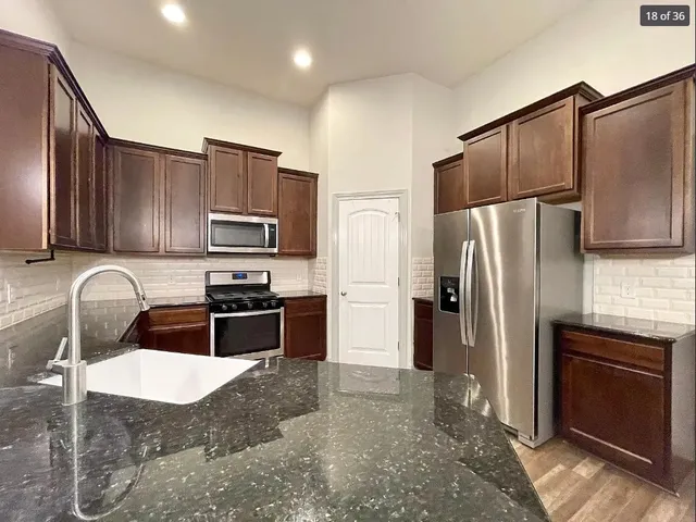 a kitchen with granite countertop stainless steel appliances and refrigerator
