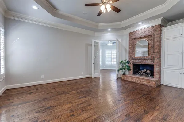 a view of an empty room with wooden floor fireplace and a window