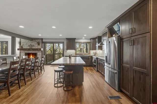 a kitchen with stainless steel appliances granite countertop a refrigerator oven a island a dining table and chairs