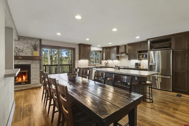 a kitchen with stainless steel appliances granite countertop a stove a refrigerator a kitchen island a table and chairs
