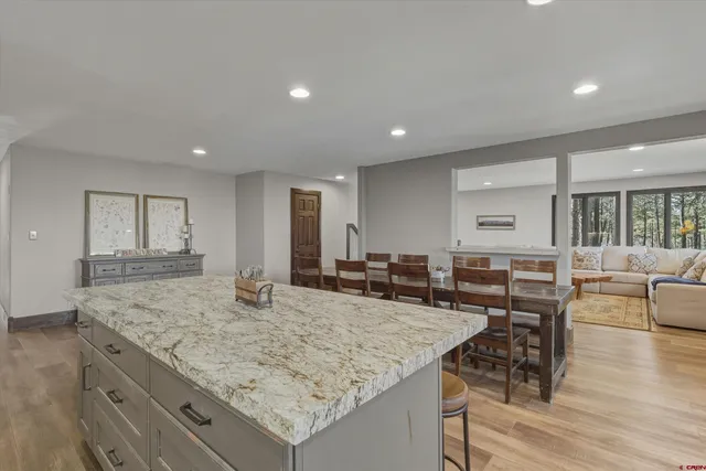 a view of kitchen island with granite countertop refrigerator stove dining table and chairs
