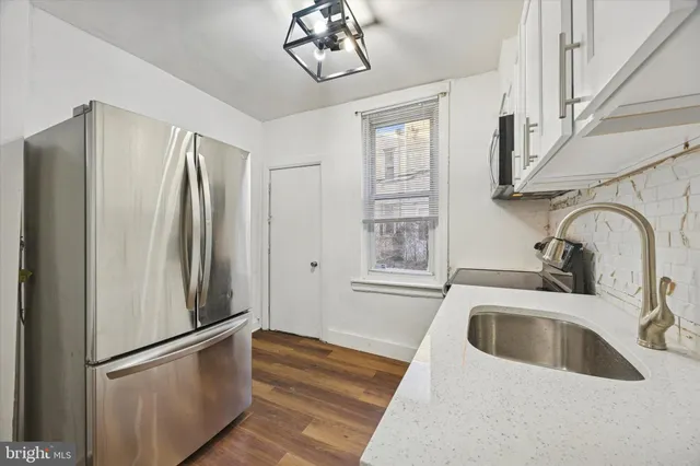 a kitchen with stainless steel appliances granite countertop a refrigerator a sink a stove and a refrigerator with wooden floor