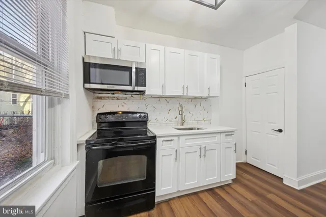 a kitchen with cabinets stainless steel appliances and wooden floor
