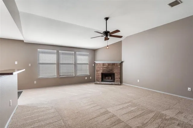 a view of an empty room with a fireplace and a window