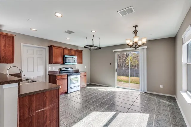 a large kitchen with kitchen island granite countertop a sink cabinets and stainless steel appliances