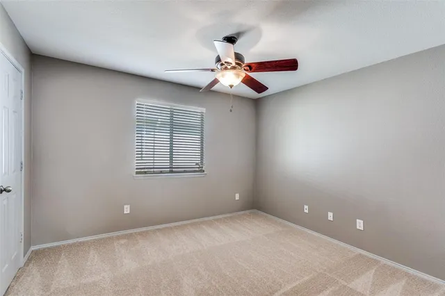 an empty room with a ceiling fan and window