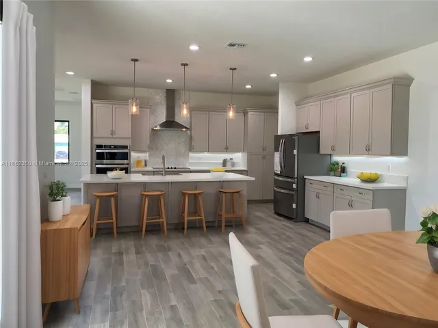 a kitchen with refrigerator a sink and chairs