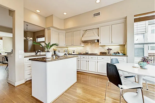 a kitchen with kitchen island granite countertop a sink cabinets and wooden floor