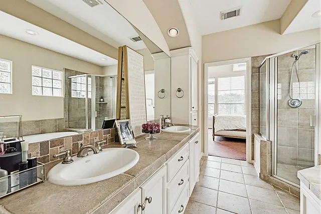 a bathroom with a double vanity sink a toilet a mirror and shower