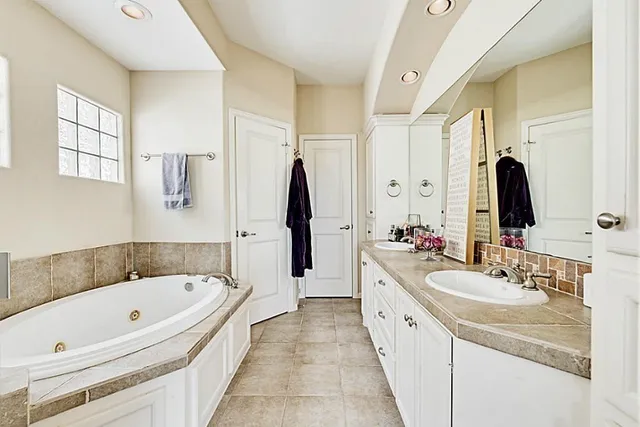 a spacious bathroom with a bathtub sink and mirror