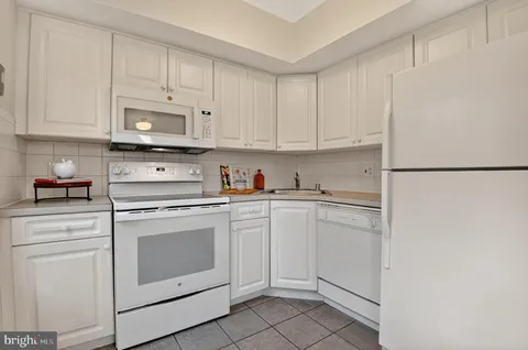 a kitchen with white cabinets and white appliances