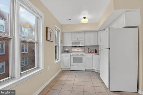 a kitchen with white cabinets and white appliances