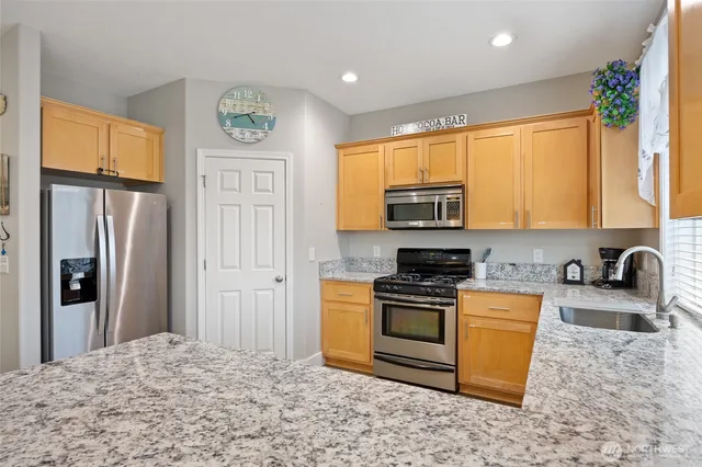 a kitchen with stainless steel appliances granite countertop a stove a refrigerator and a sink
