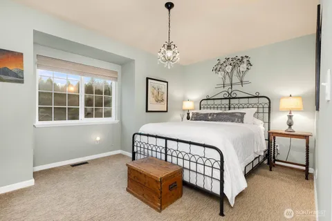 a bedroom with a bed chandelier and windows