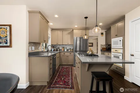 a kitchen with kitchen island granite countertop a sink a counter top space stainless steel appliances and cabinets