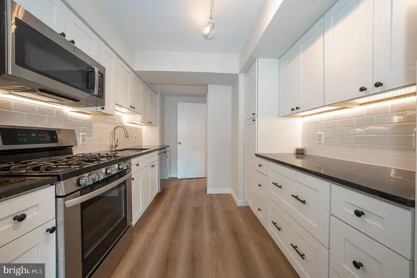 a kitchen with stainless steel appliances granite countertop a stove a sink and a microwave