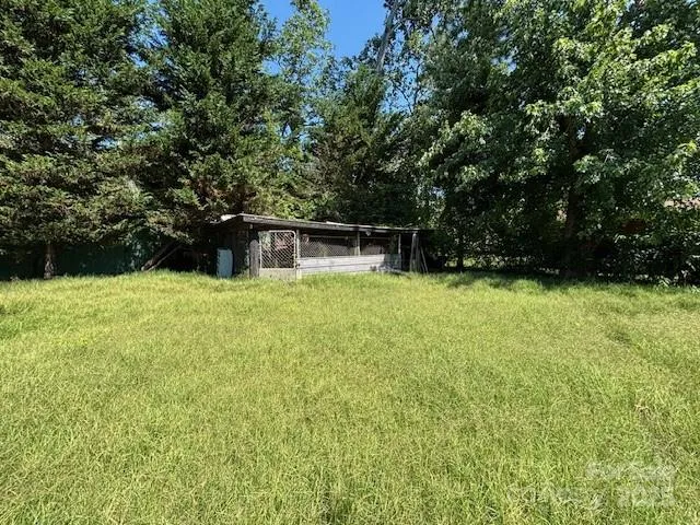 a swimming pool that is in a big yard with large trees