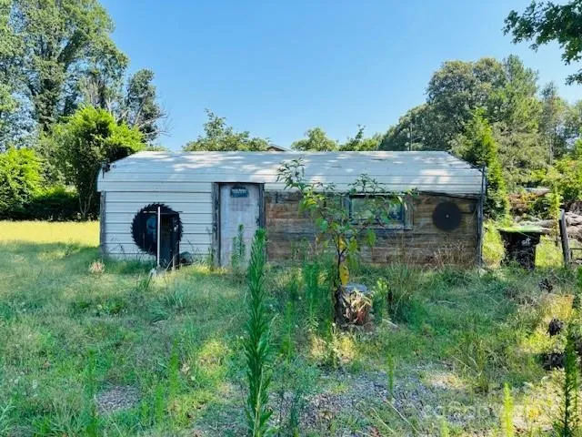 a backyard of a house with plants and large tree