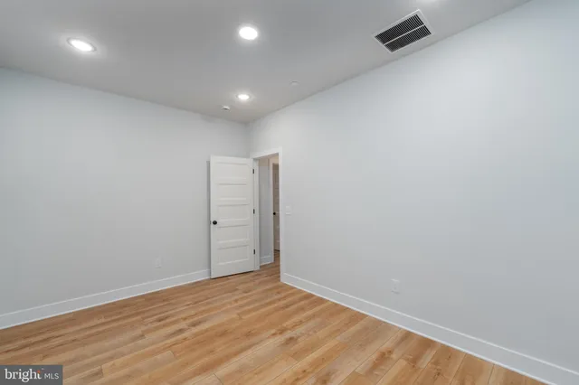 an empty room with wooden floor chandelier and windows