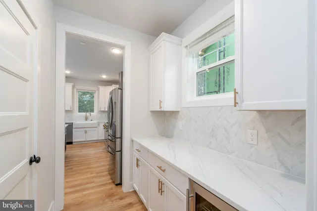 a kitchen with white cabinets and a window
