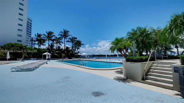 a view of a swimming pool with a yard and palm trees