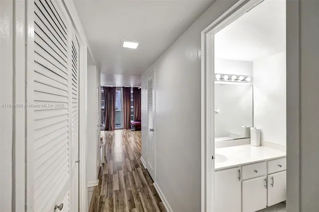 a view of a hallway with wooden floor and a bathroom