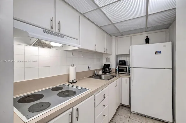 a kitchen with a sink a refrigerator and cabinets
